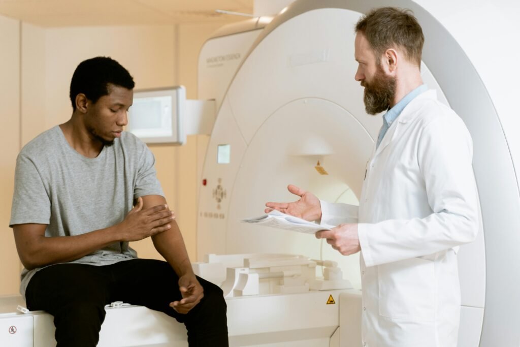 A doctor consults with a patient by an MRI scanner in a medical facility.